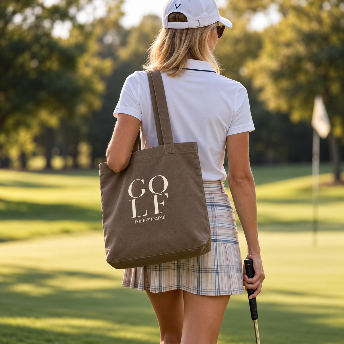 The Clubhouse Tote, a walnut canvas golf tote with bold GOLF wordmark print by Fore & Femme, styled for a day at the club