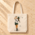 The Swing Tote flat lay, a natural canvas golf tote with swinging golfer artwork by Fore & Femme