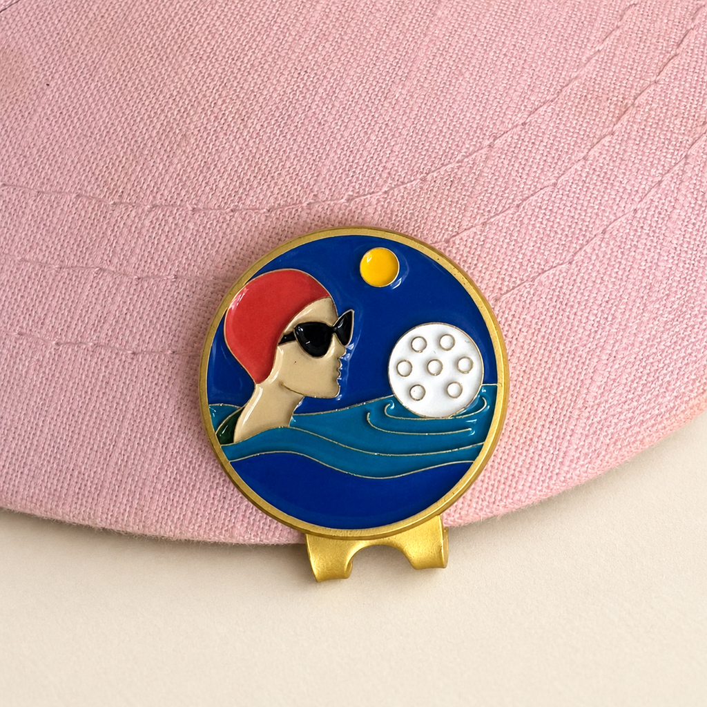 Water Hazard golf ball marker by Fore & Femme clipped to a pink linen cap
